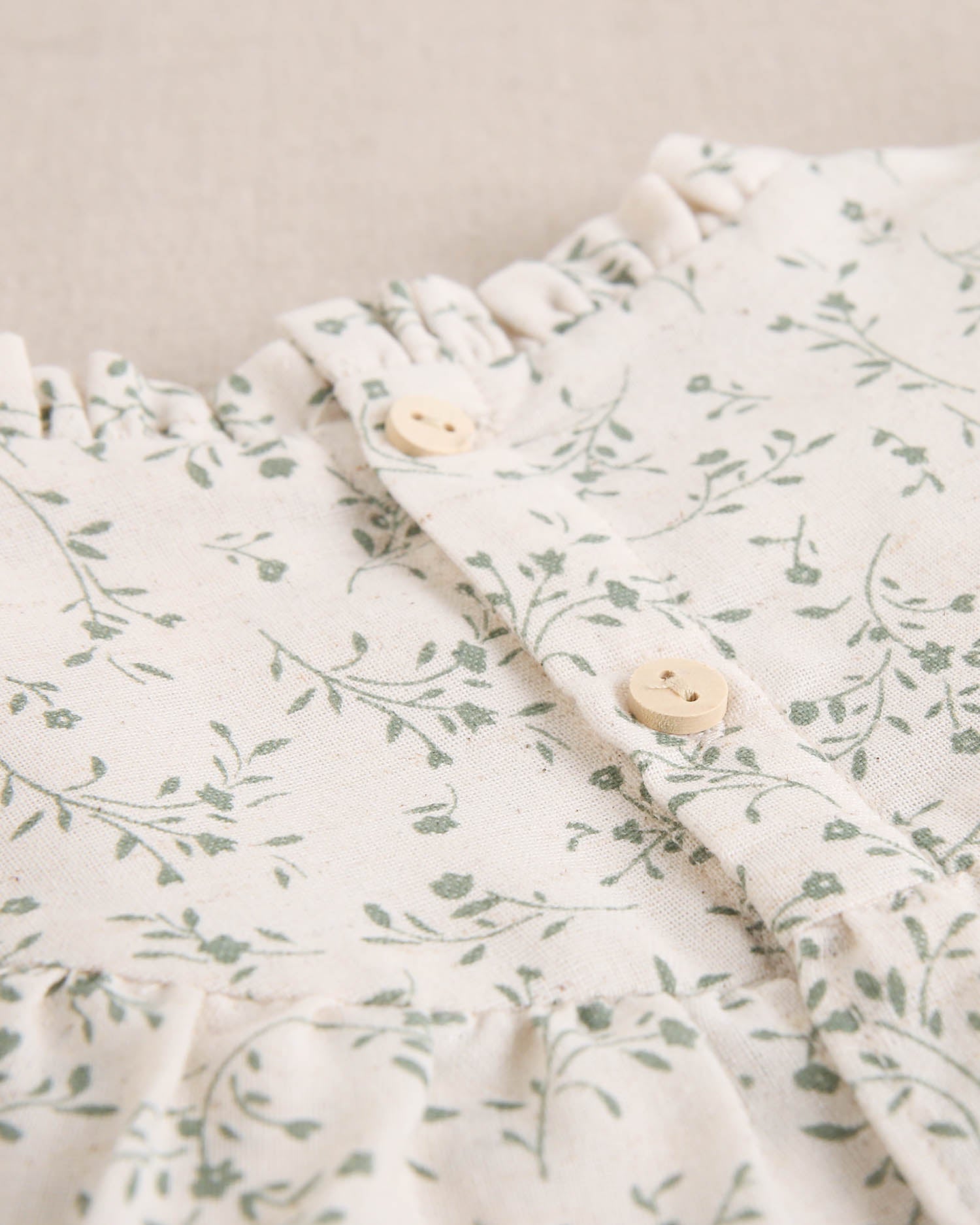 Vestido de niña color crudo con estampado floral verde y detalle de volante