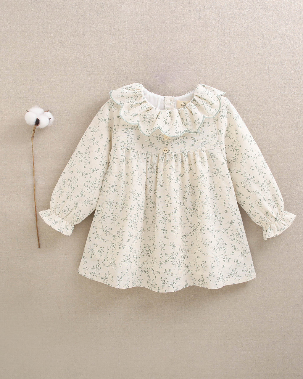 Vestido de niña color crudo con estampado floral verde y detalle de volante