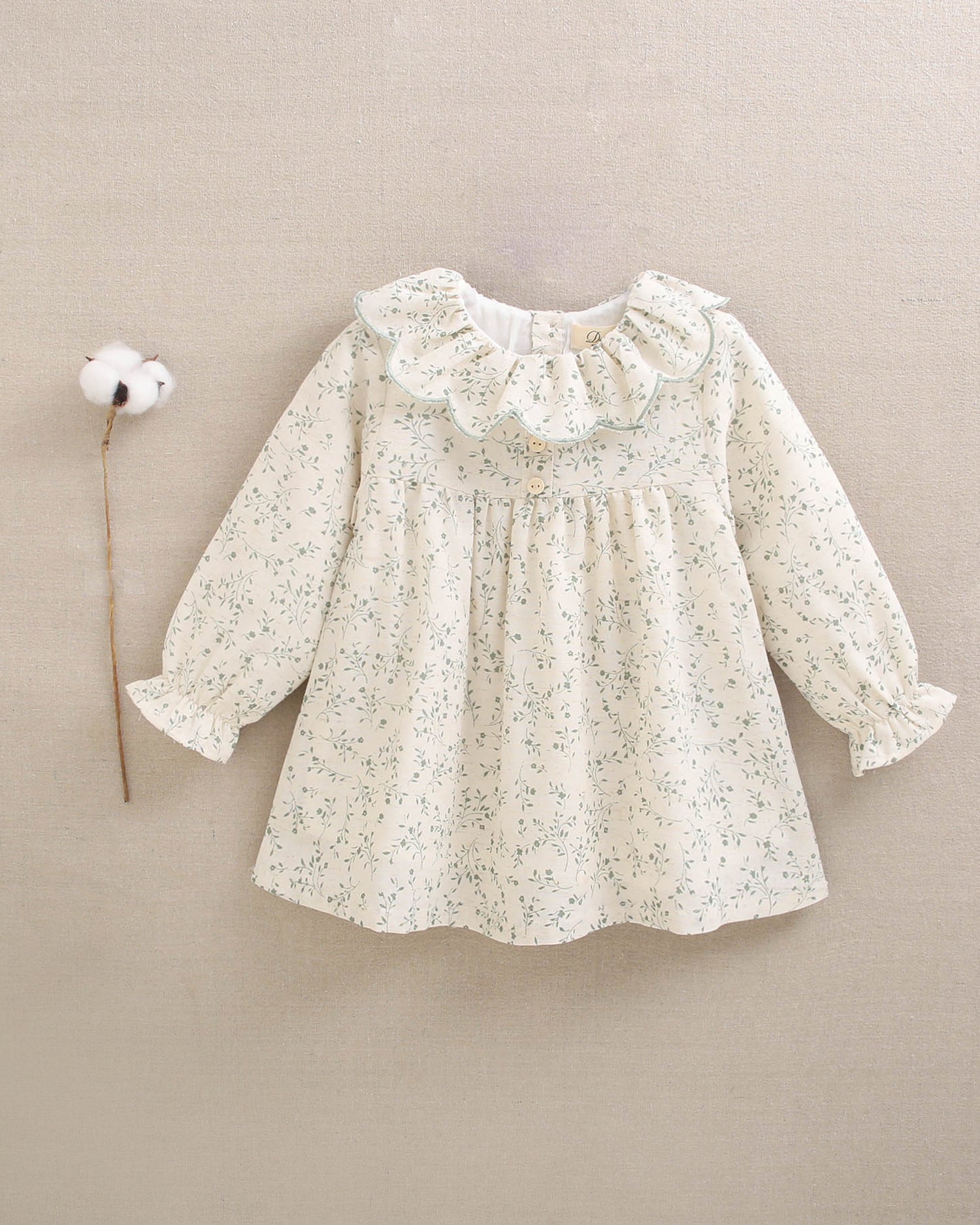 Vestido de niña color crudo con estampado floral verde y detalle de volante