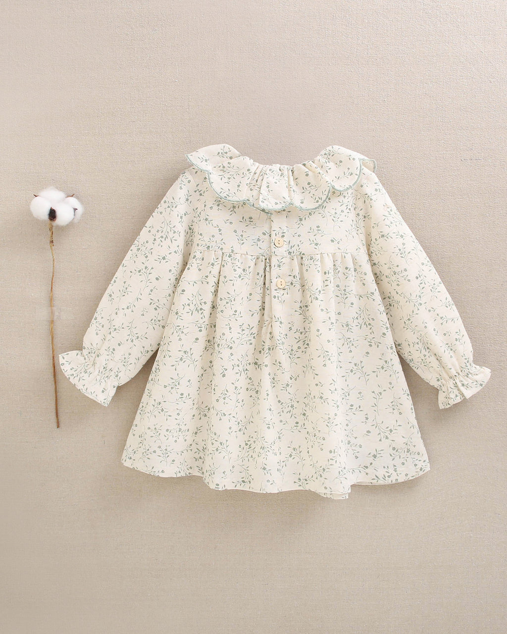 Vestido de niña color crudo con estampado floral verde y detalle de volante