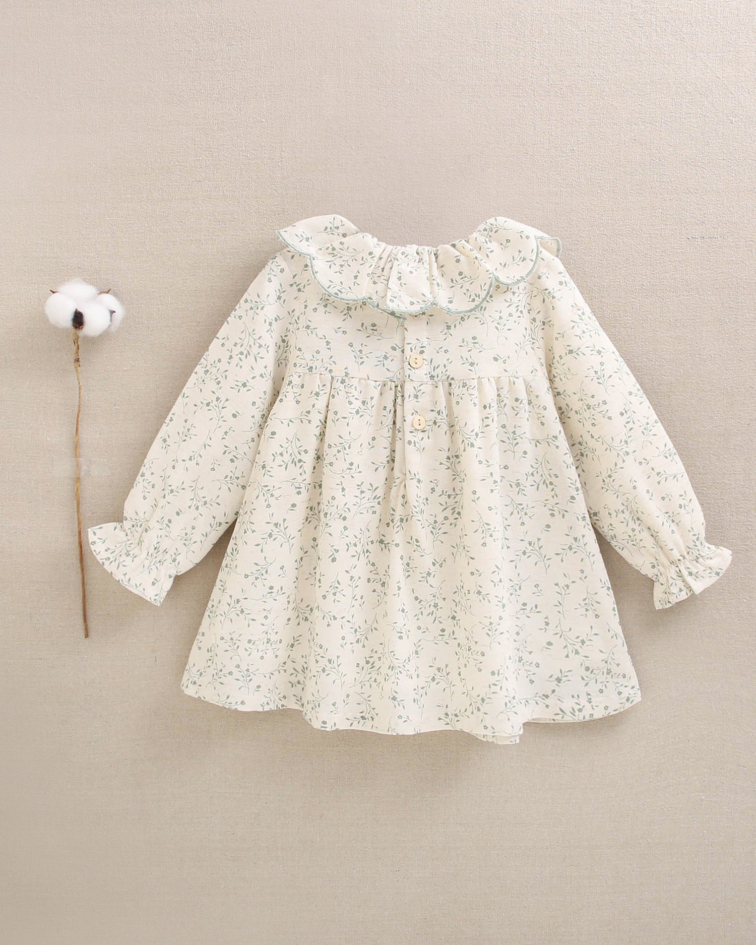 Vestido de niña color crudo con estampado floral verde y detalle de volante