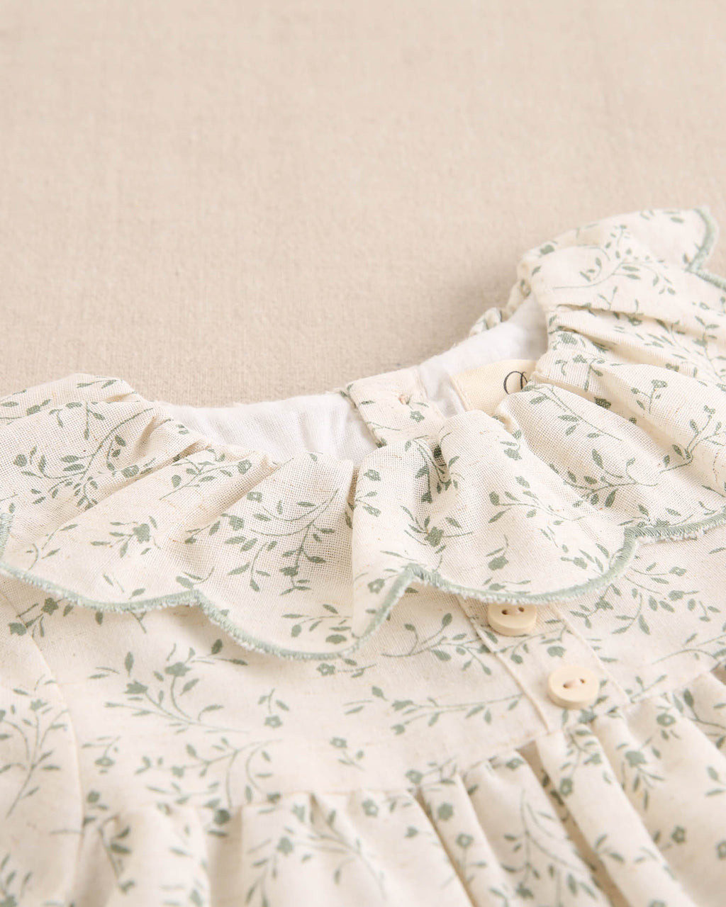 Vestido de niña color crudo con estampado floral verde y detalle de volante