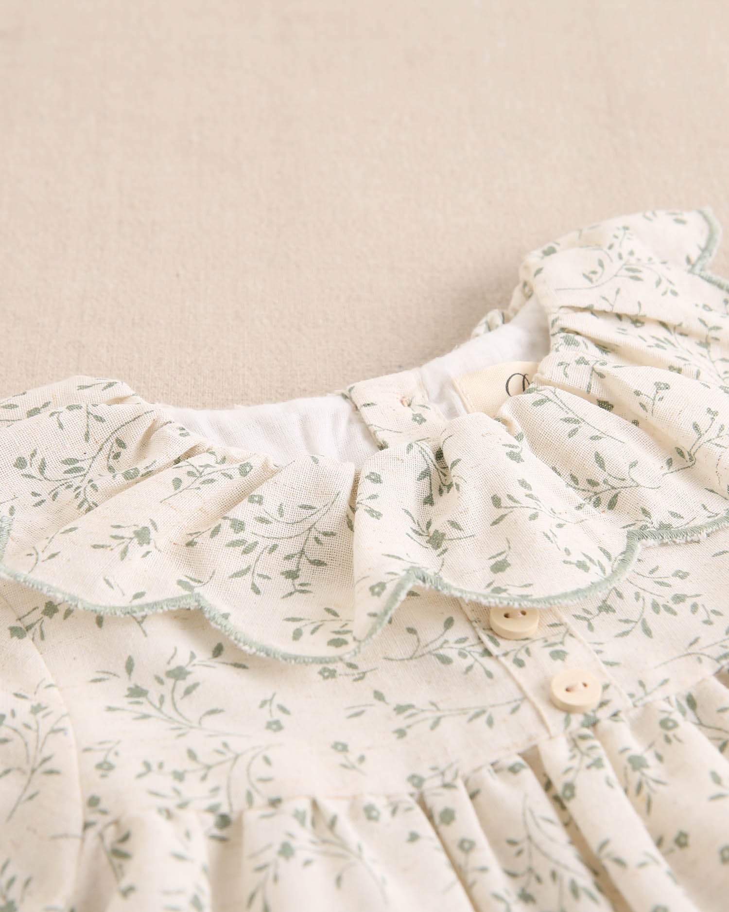 Vestido de niña color crudo con estampado floral verde y detalle de volante