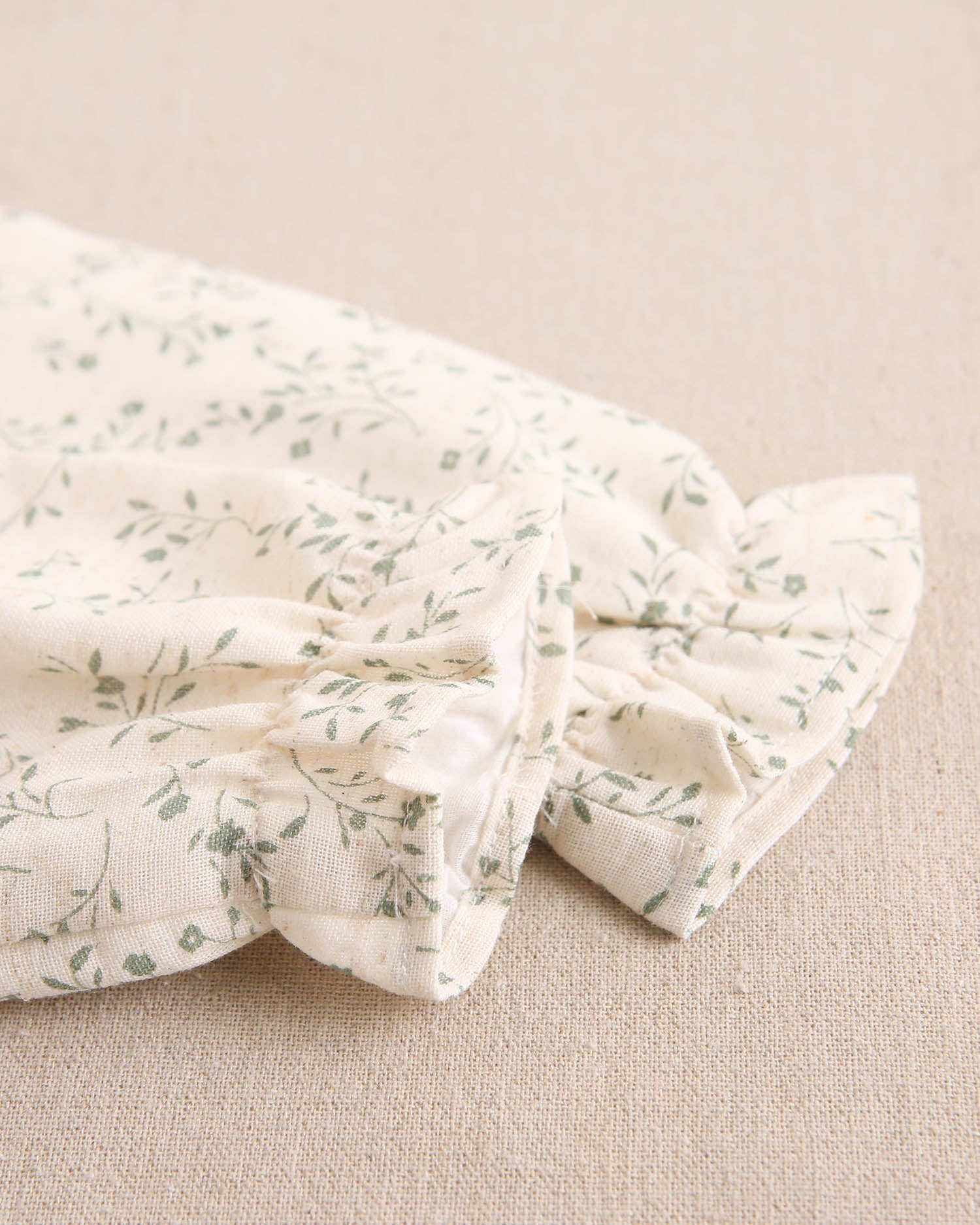 Vestido de niña color crudo con estampado floral verde y detalle de volante