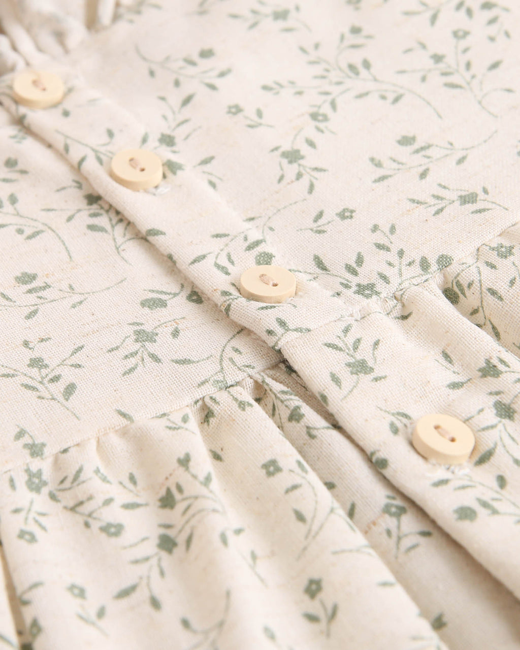 Vestido de niña color crudo con estampado floral verde y detalle de volante