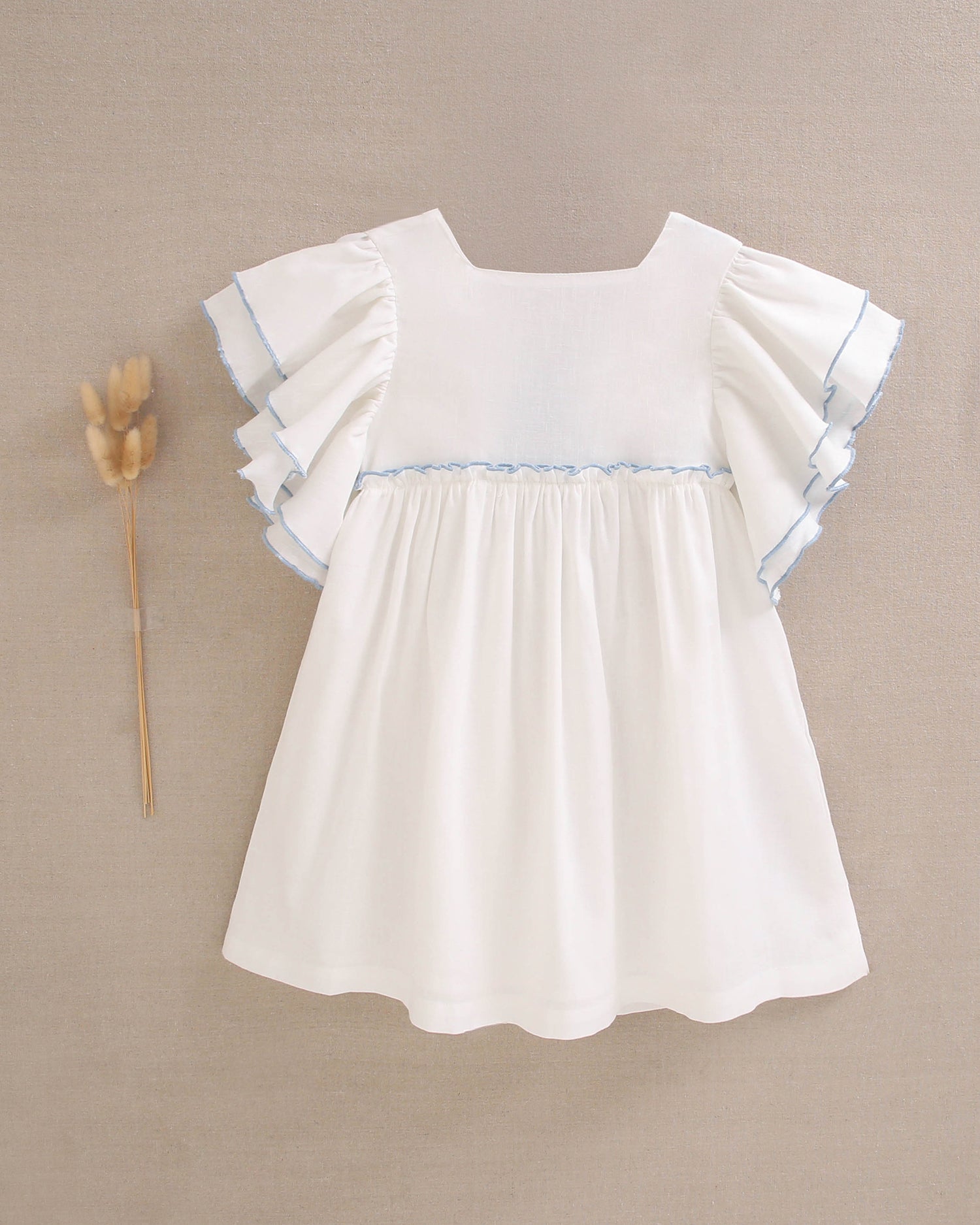 Vestido niña blanco con bordes en azul y lazo en espalda de plumeti azul