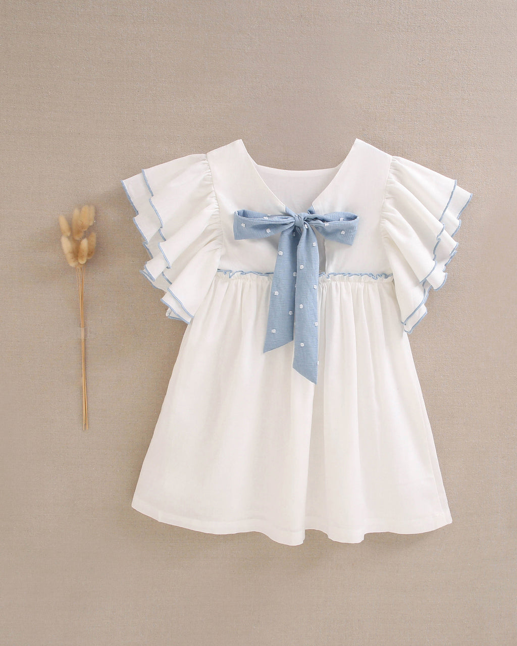 Vestido niña blanco con bordes en azul y lazo en espalda de plumeti azul
