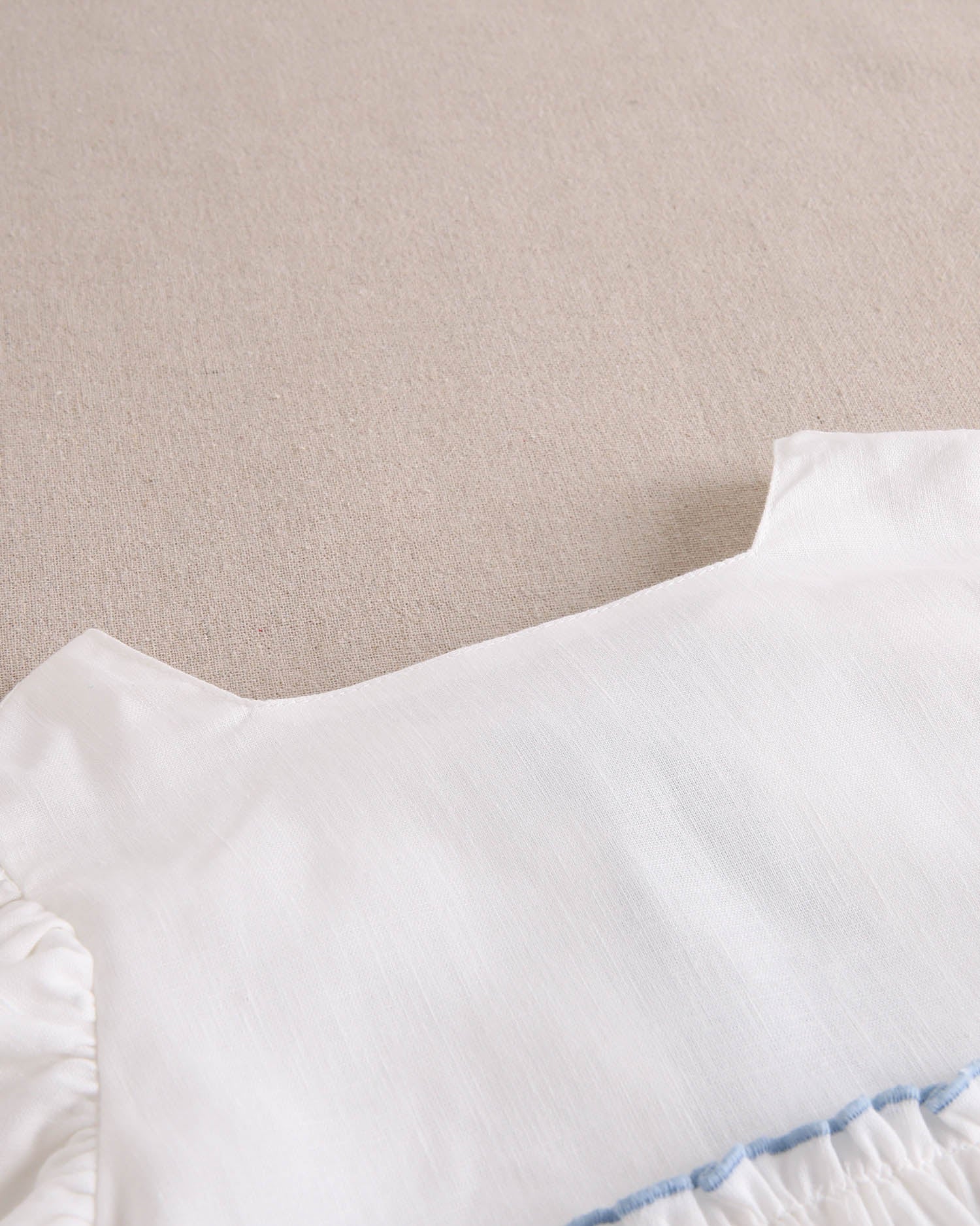 Vestido niña blanco con bordes en azul y lazo en espalda de plumeti azul