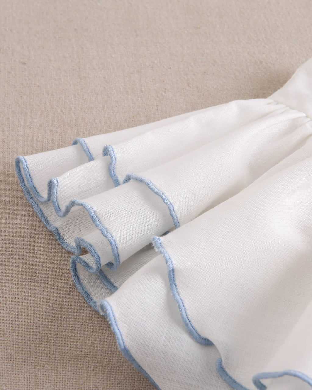Vestido niña blanco con bordes en azul y lazo en espalda de plumeti azul