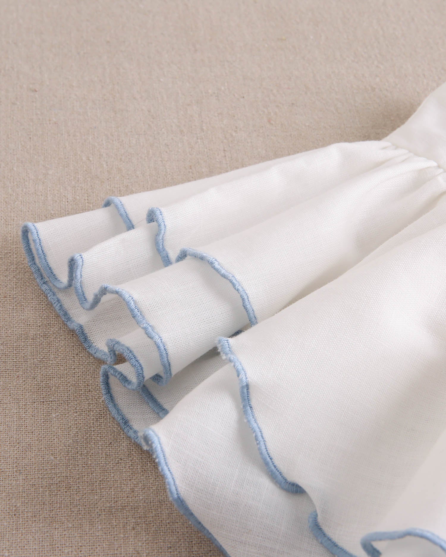 Vestido niña blanco con bordes en azul y lazo en espalda de plumeti azul