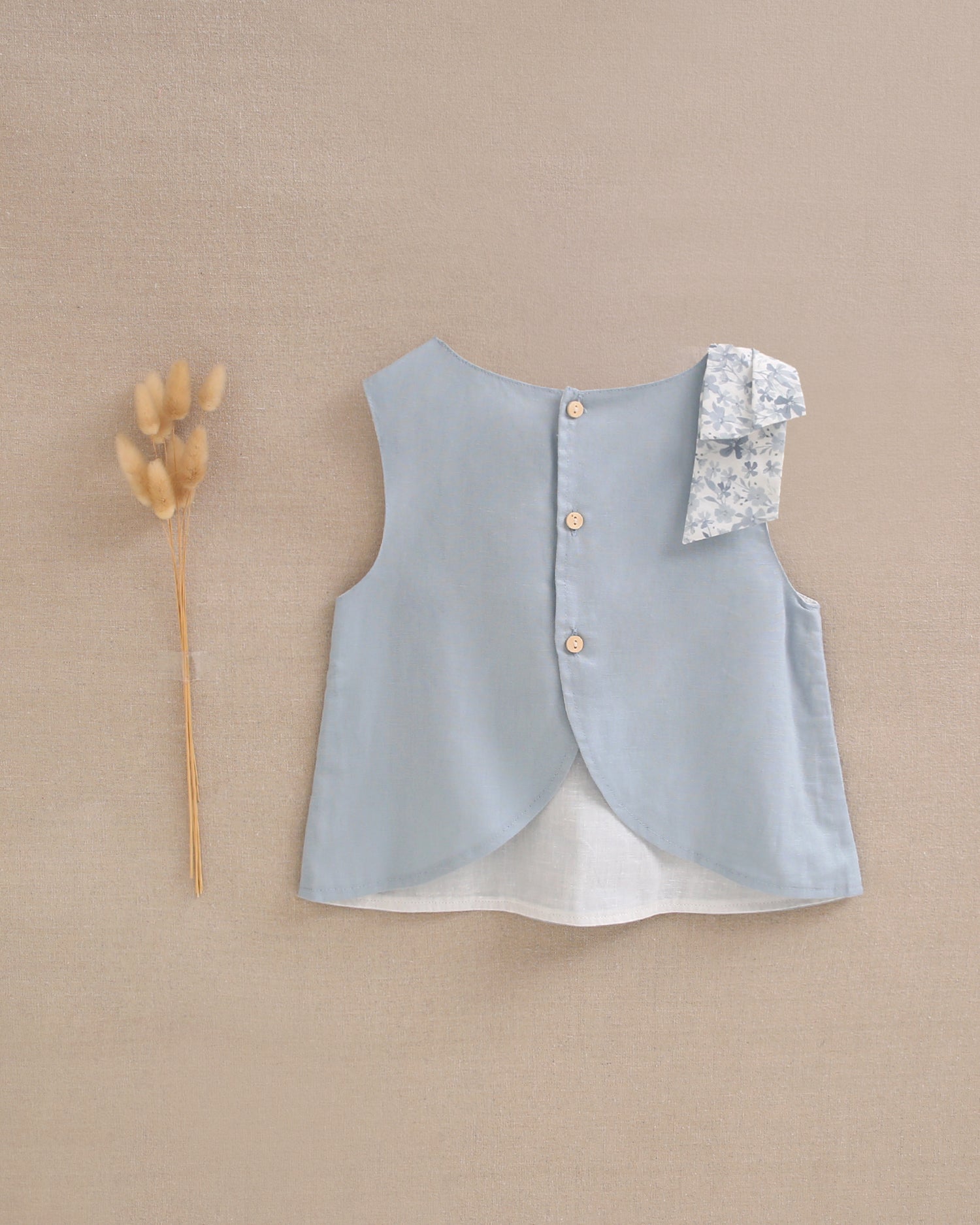 Blusa niña azul con lazo en tirante de flores  y abertura espalda