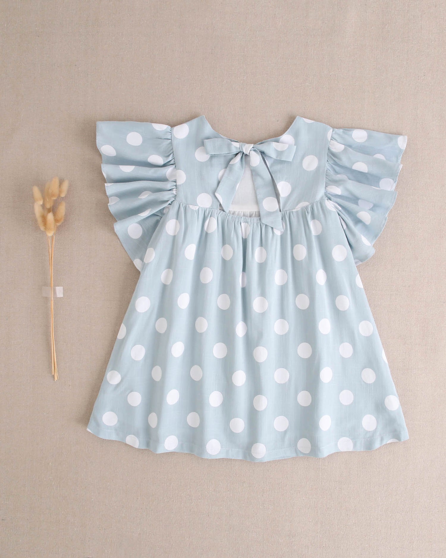 Vestido de niña azul cielo con lunares blancos y lazo en espalda