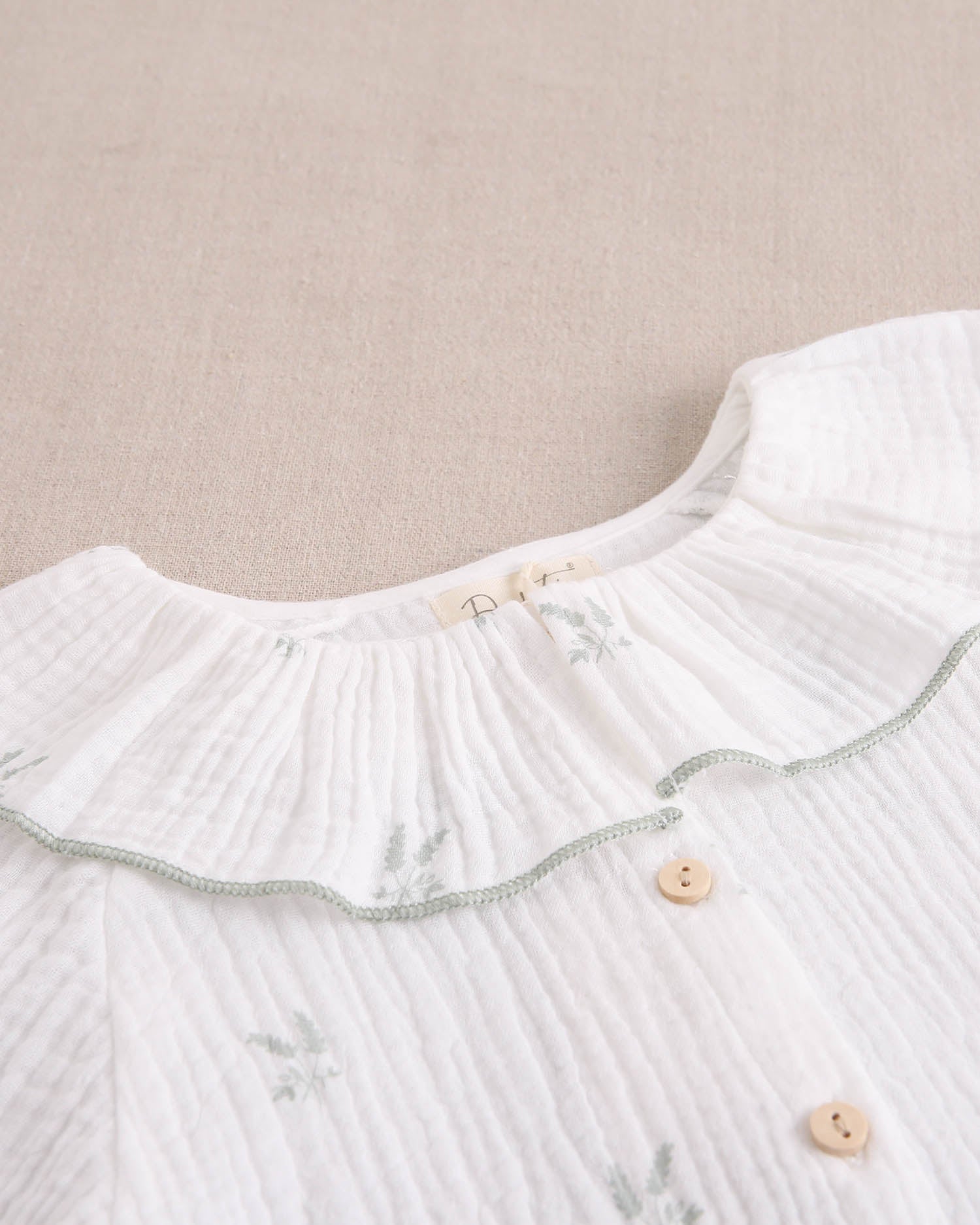 Blusa niña de muselina crudo con estampado de ramas verde pastel y cuello volante