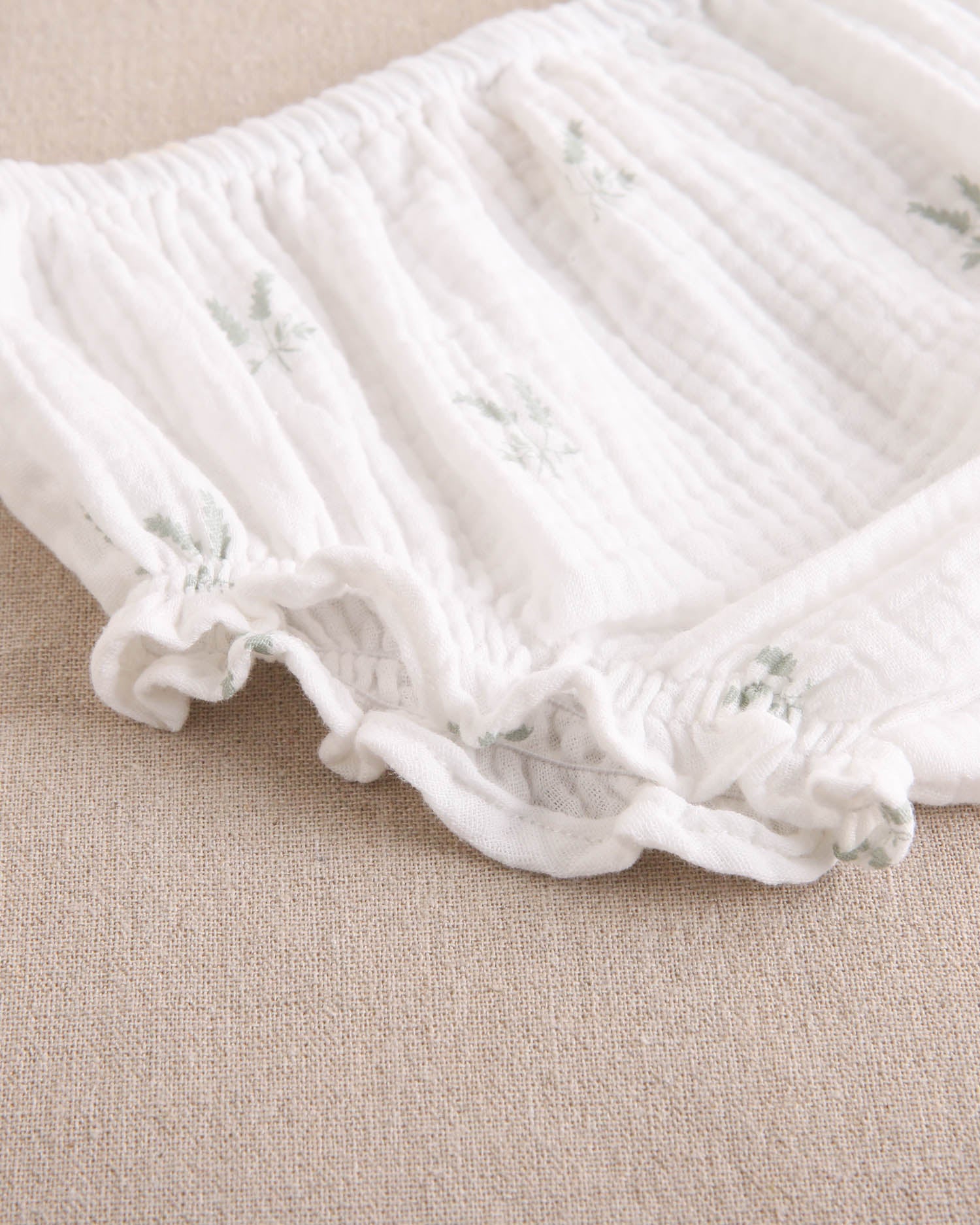 Vestido bebé niña crudo con estampado de ramas verde pastel