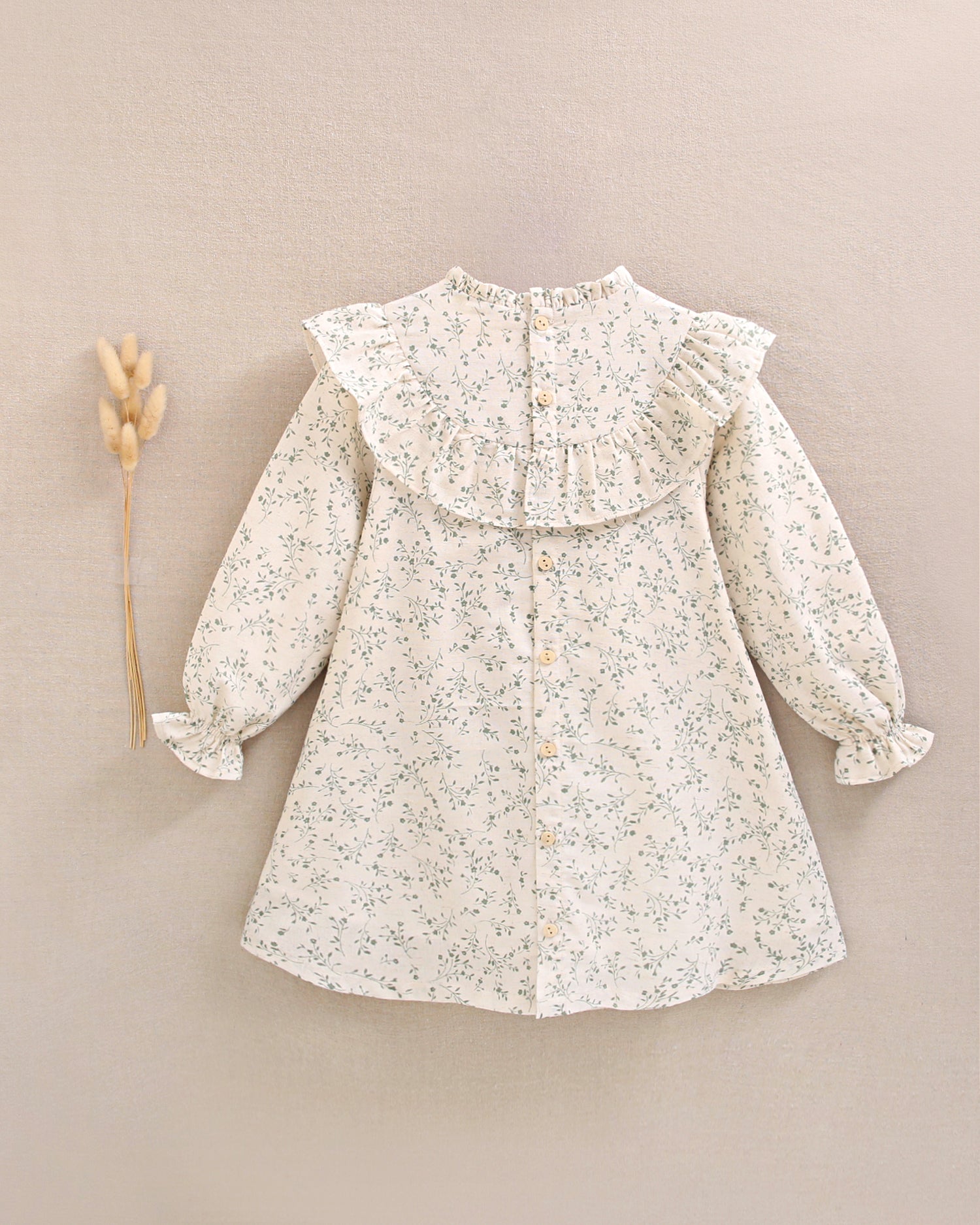 Vestido de niña color crudo con estampado floral verde y detalle de volante