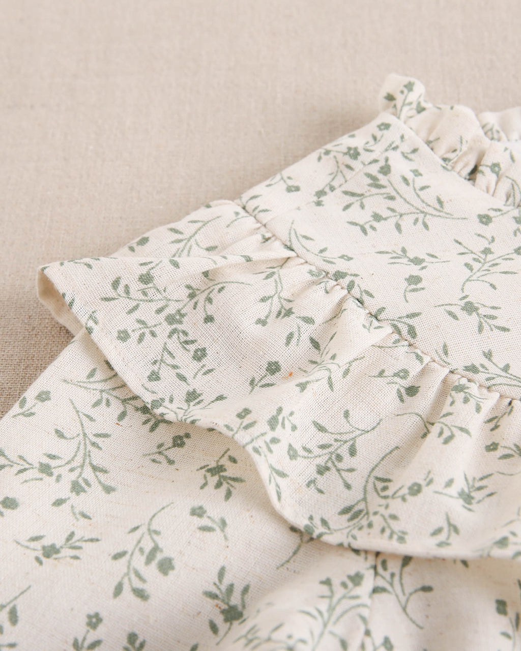Vestido de niña color crudo con estampado floral verde y detalle de volante