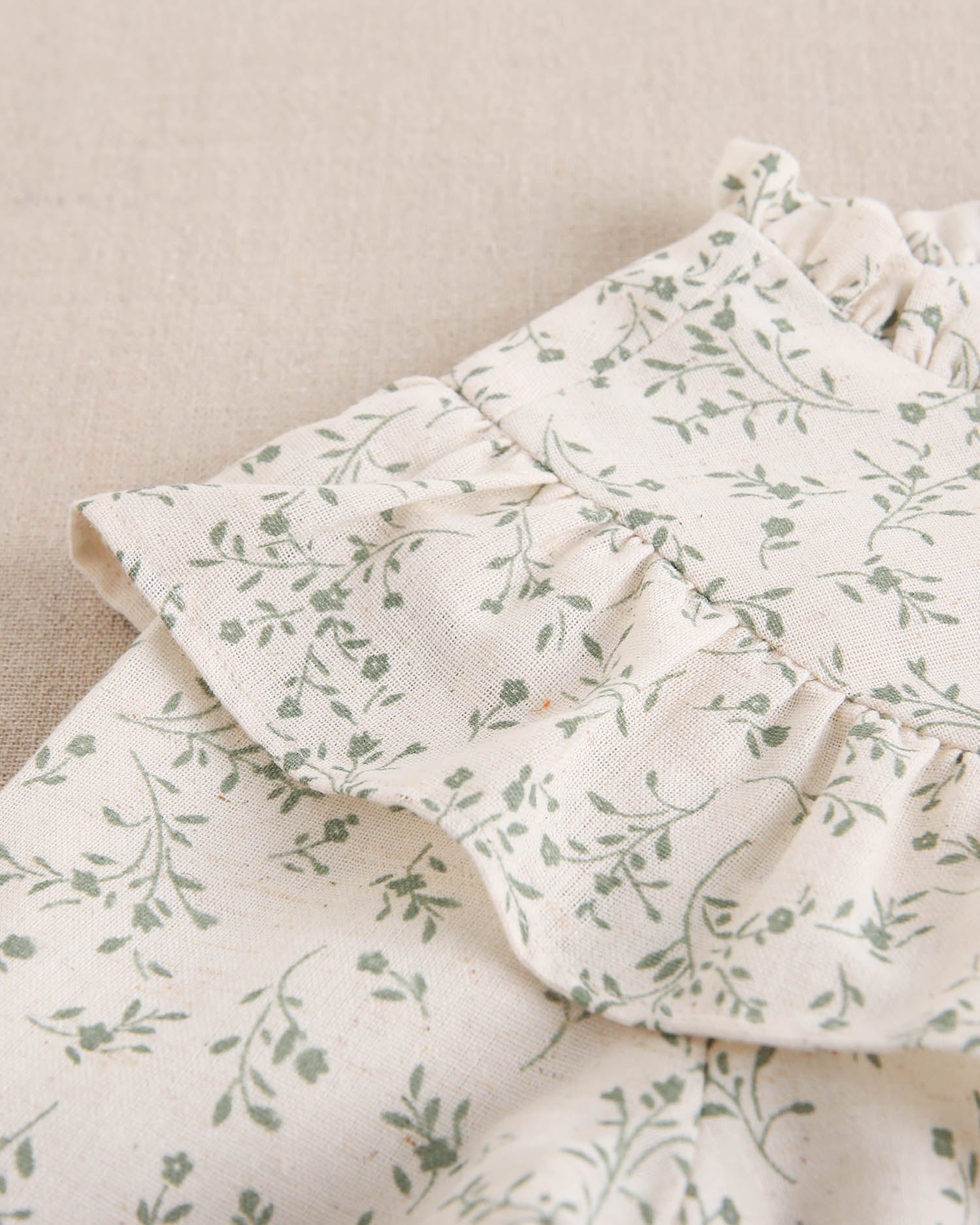 Vestido de niña color crudo con estampado floral verde y detalle de volante