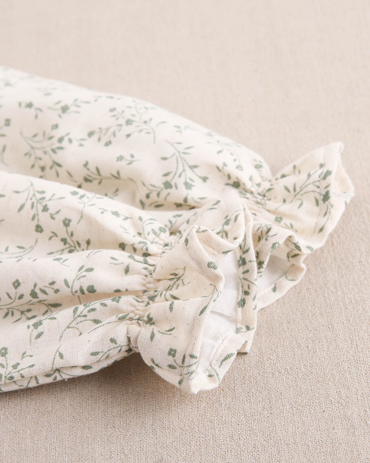 Vestido de niña color crudo con estampado floral verde y detalle de volante