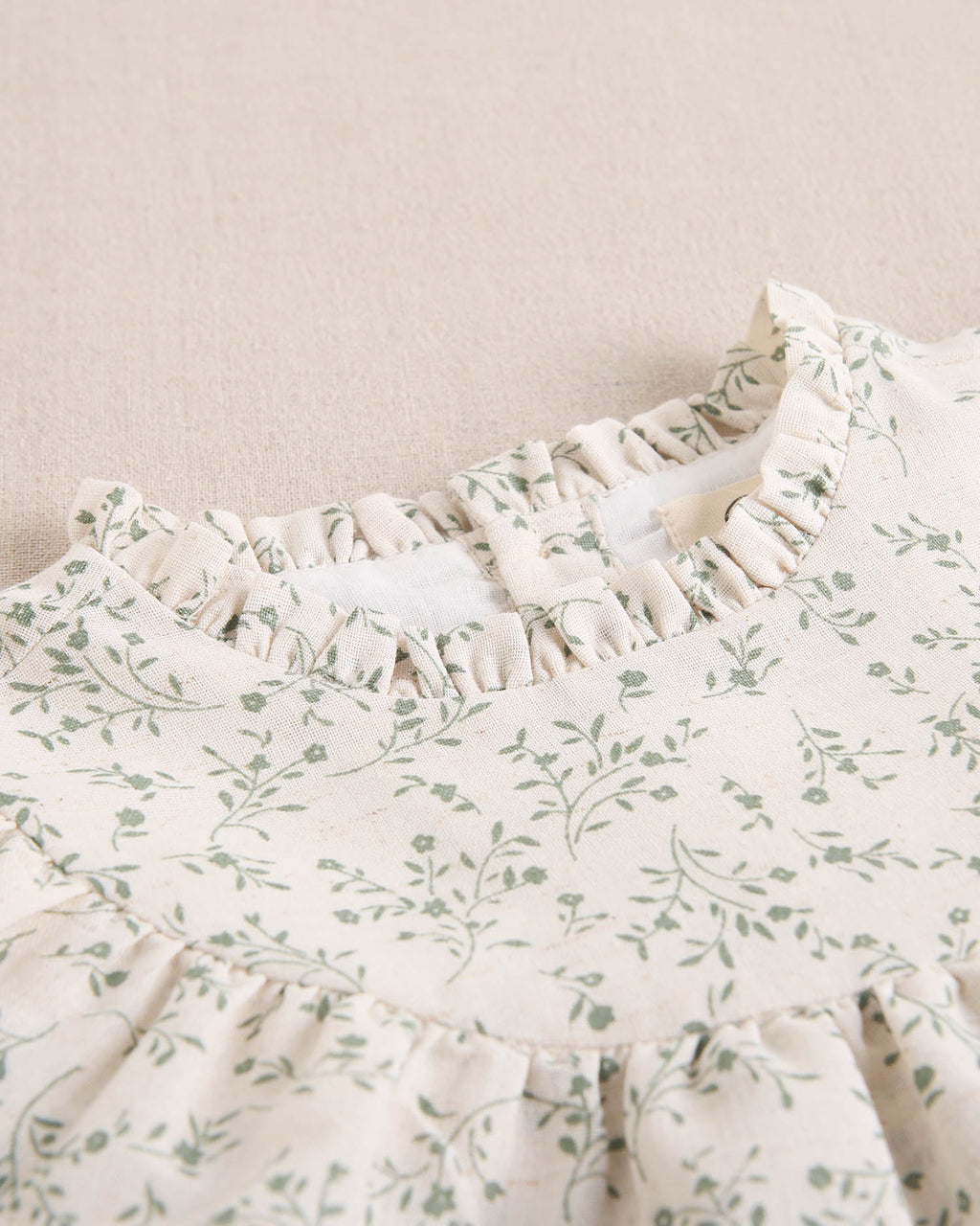 Vestido de niña color crudo con estampado floral verde y detalle de volante