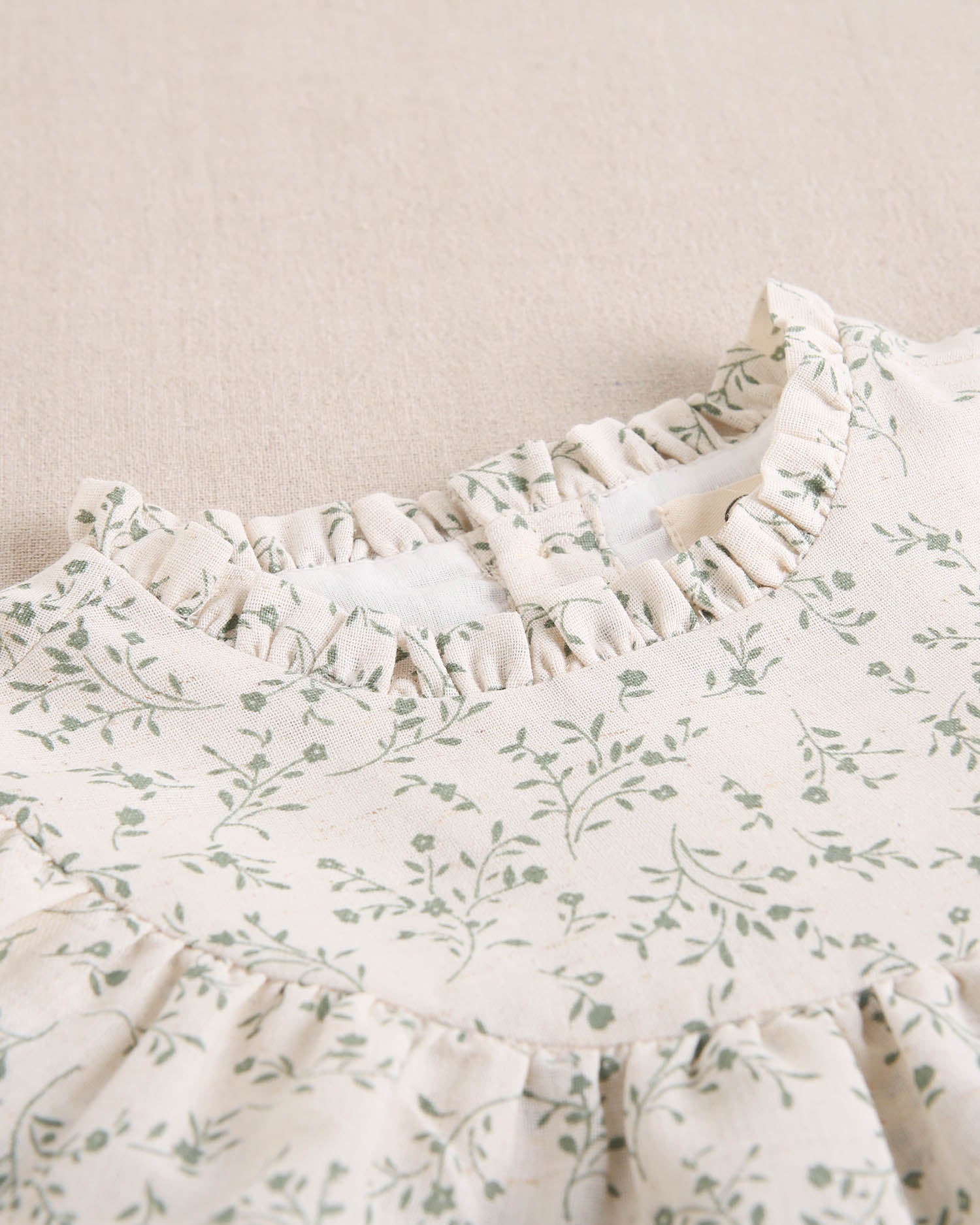 Vestido de niña color crudo con estampado floral verde y detalle de volante