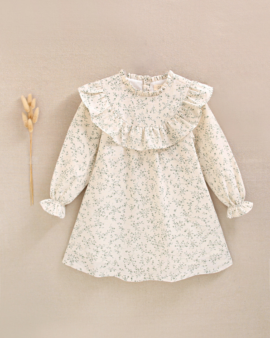 Vestido de niña color crudo con estampado floral verde y detalle de volante