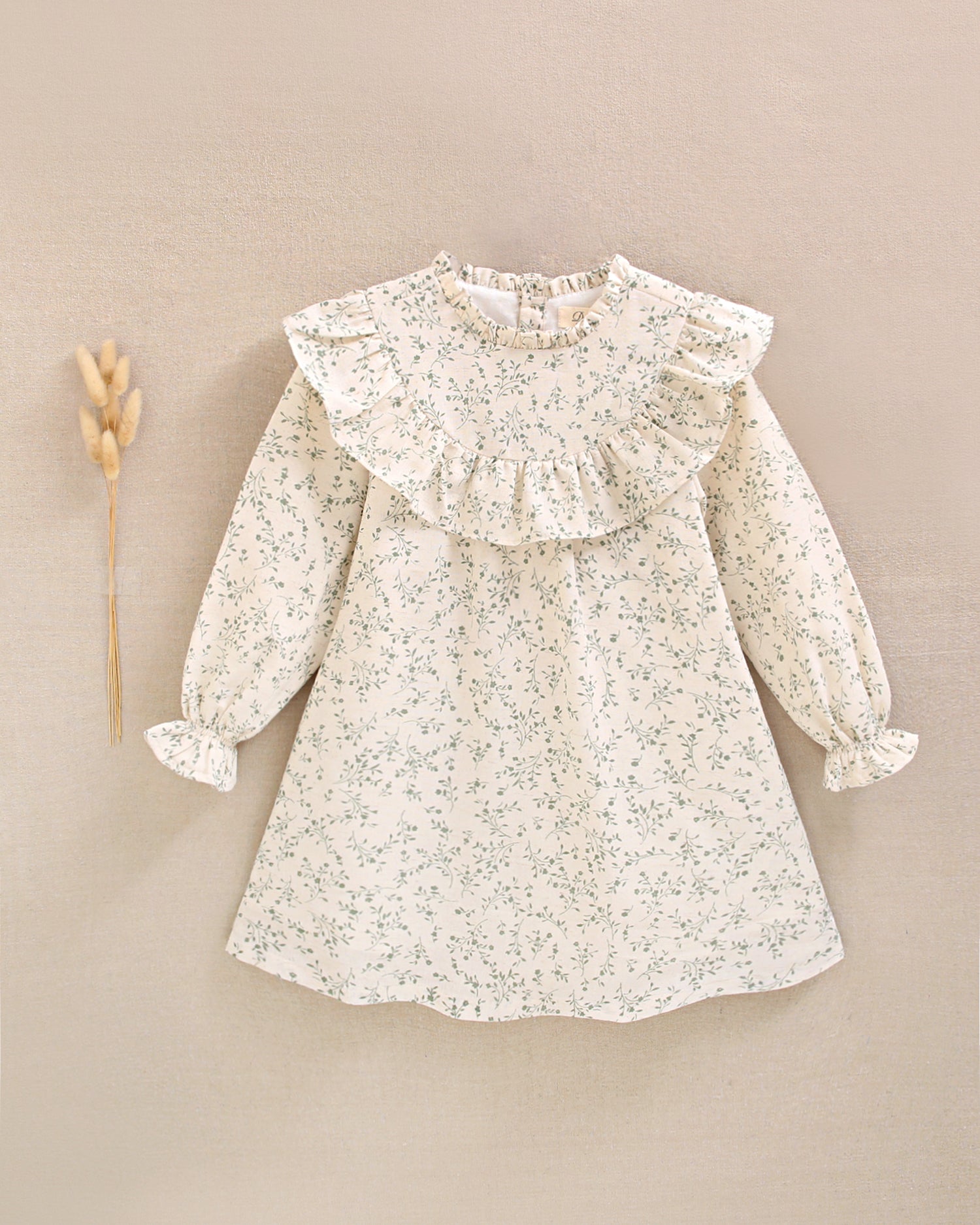 Vestido de niña color crudo con estampado floral verde y detalle de volante