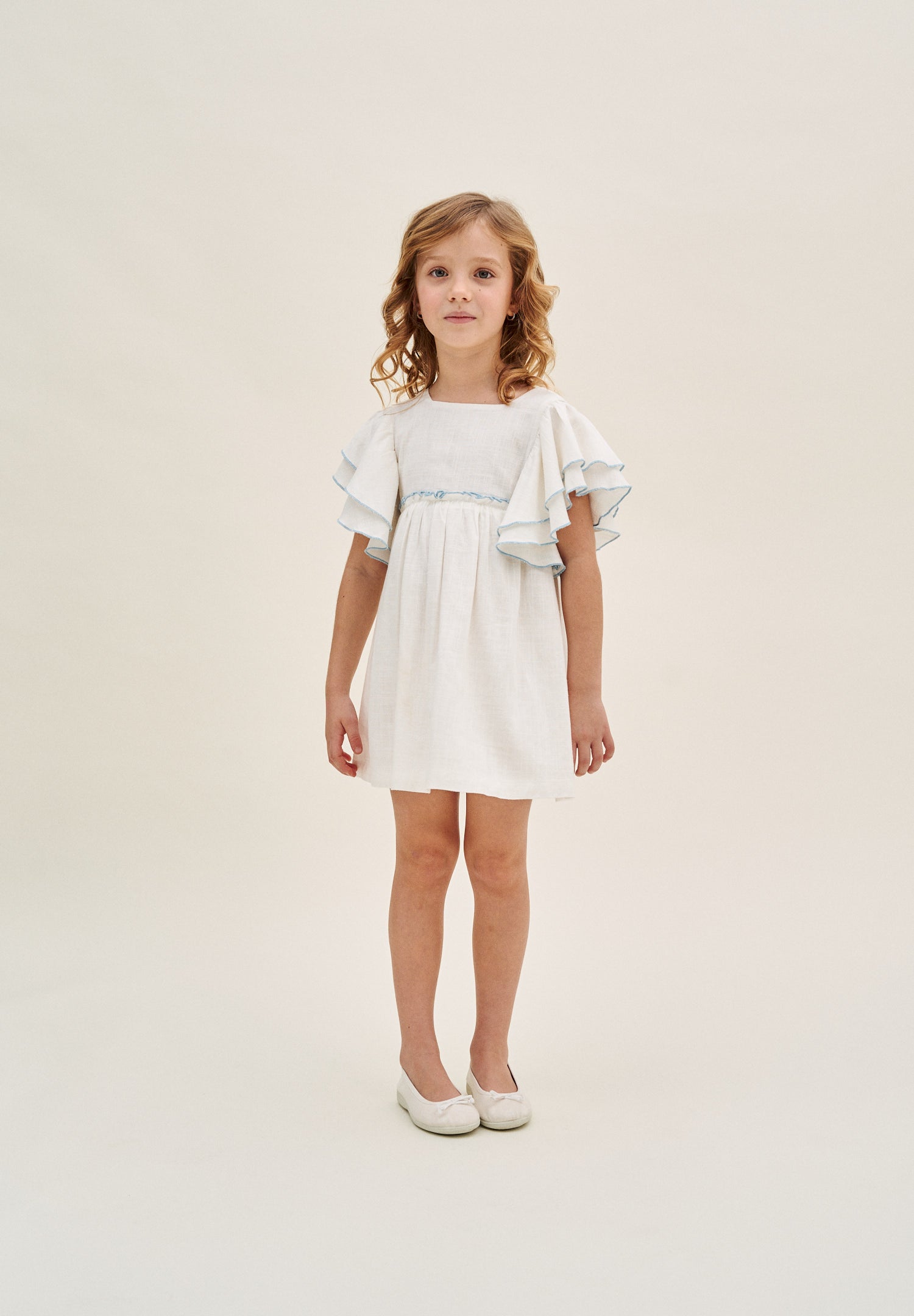 Vestido niña blanco con bordes en azul y lazo en espalda de plumeti azul