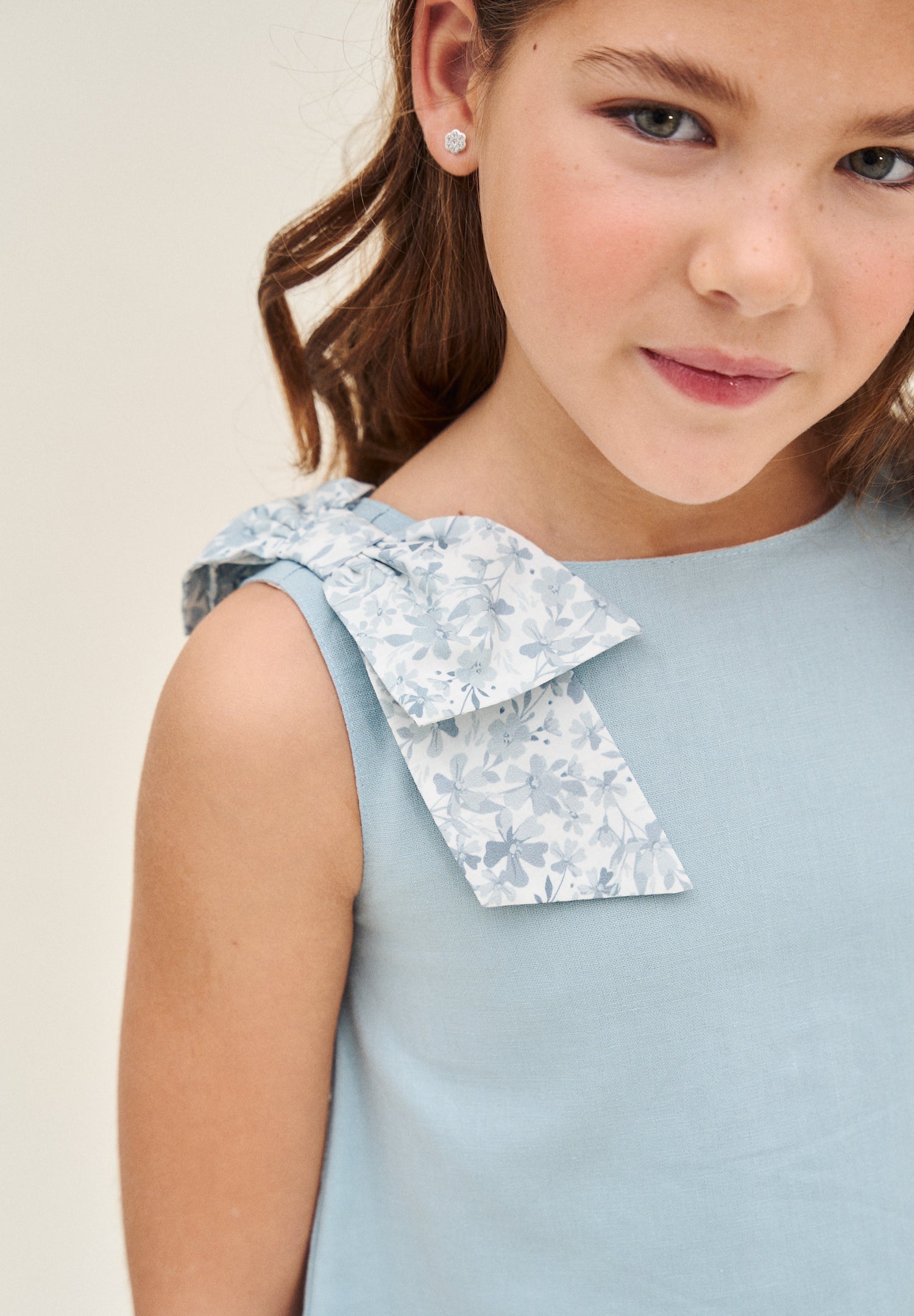 Blusa niña azul con lazo en tirante de flores  y abertura espalda