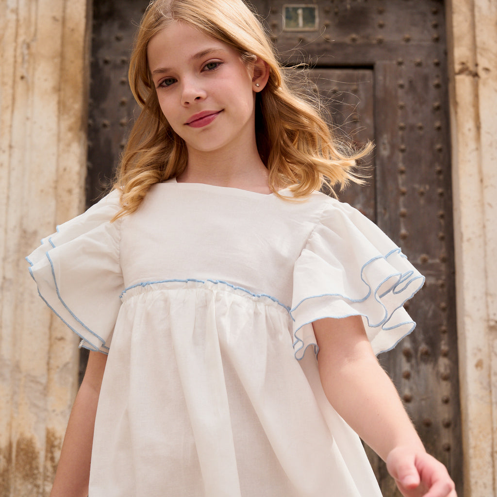 Vestido niña blanco con bordes en azul y lazo en espalda de plumeti azul