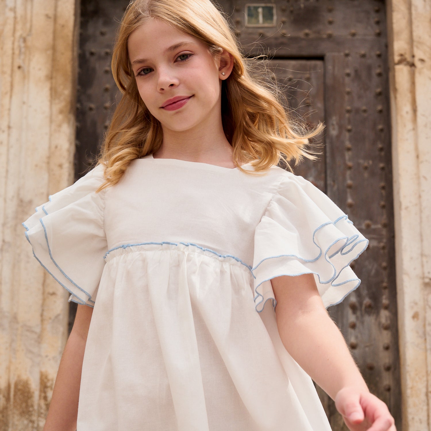 Vestido niña blanco con bordes en azul y lazo en espalda de plumeti azul