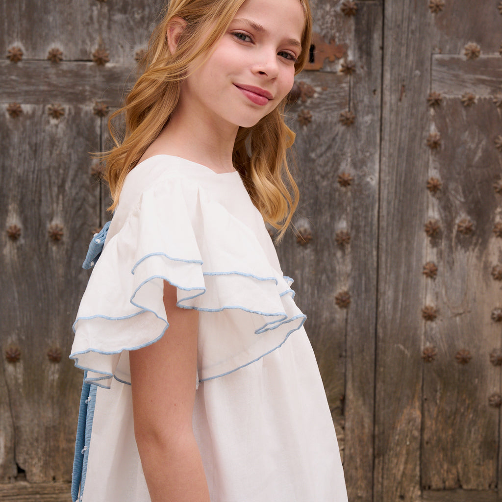 Vestido niña blanco con bordes en azul y lazo en espalda de plumeti azul