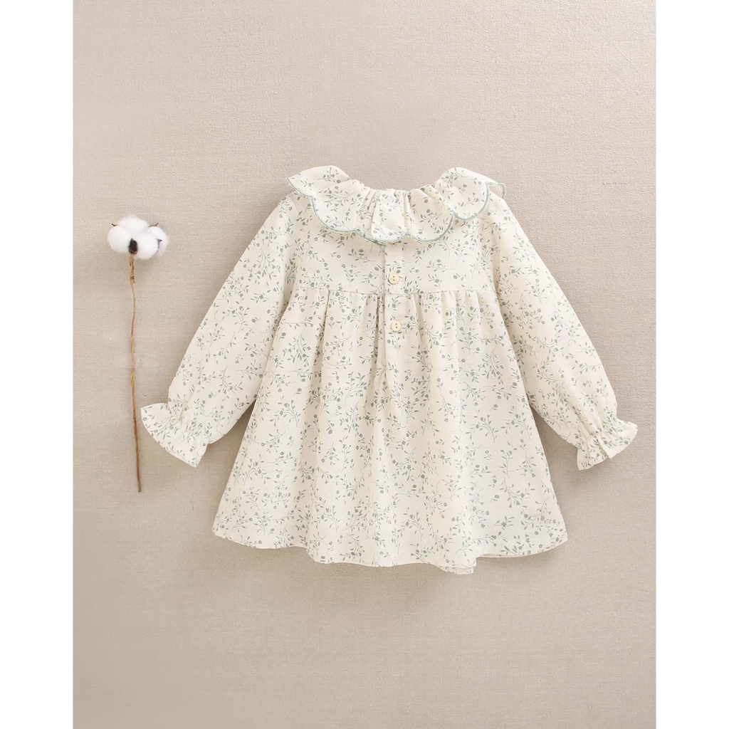 Vestido de bebé color crudo con estampado floral verde y volante en el cuello