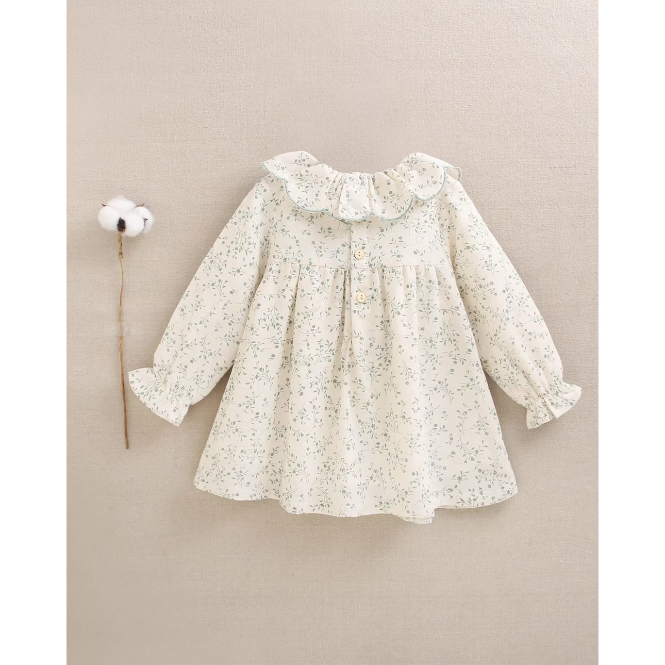 Vestido de bebé color crudo con estampado floral verde y volante en el cuello