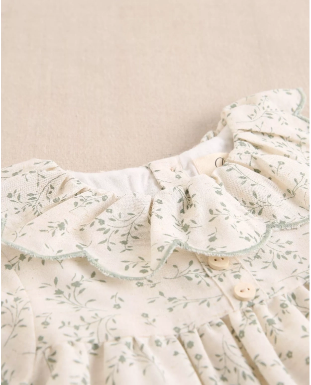 Vestido de bebé color crudo con estampado floral verde y volante en el cuello